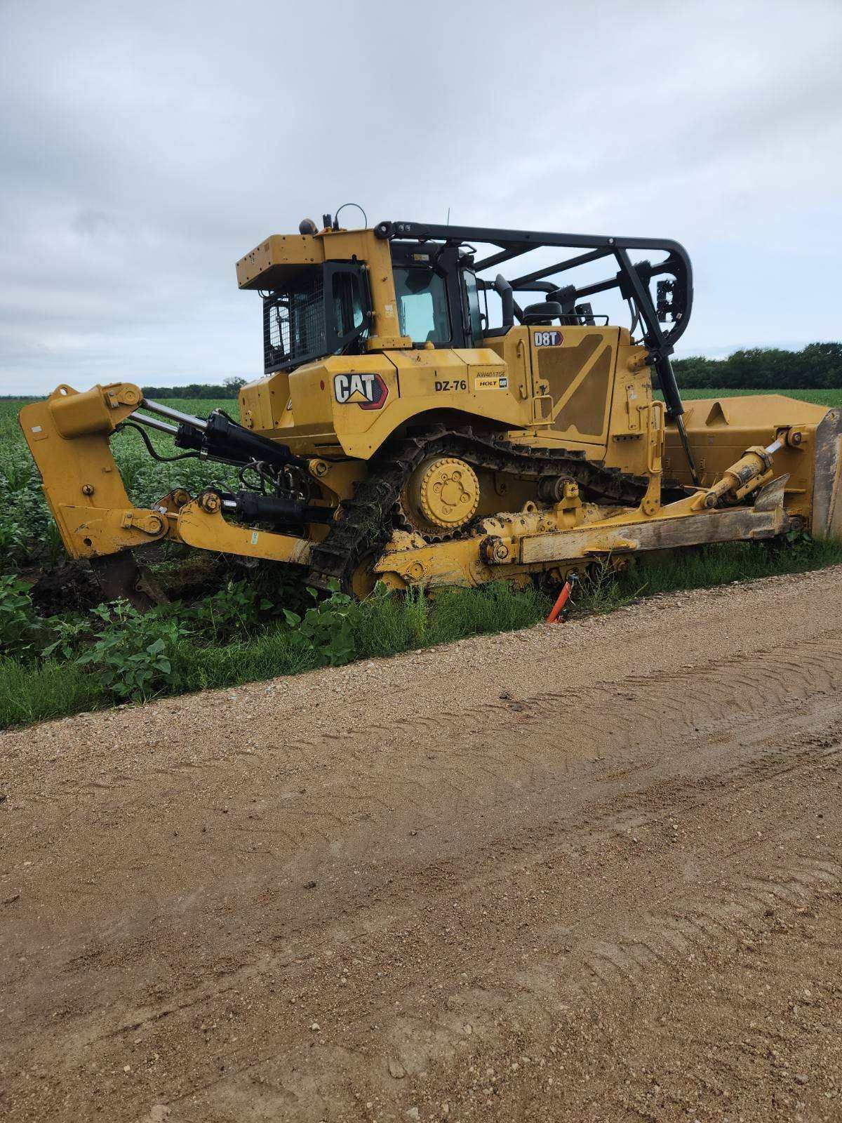 A yellow bulldozer is parked on the side of a dirt road.