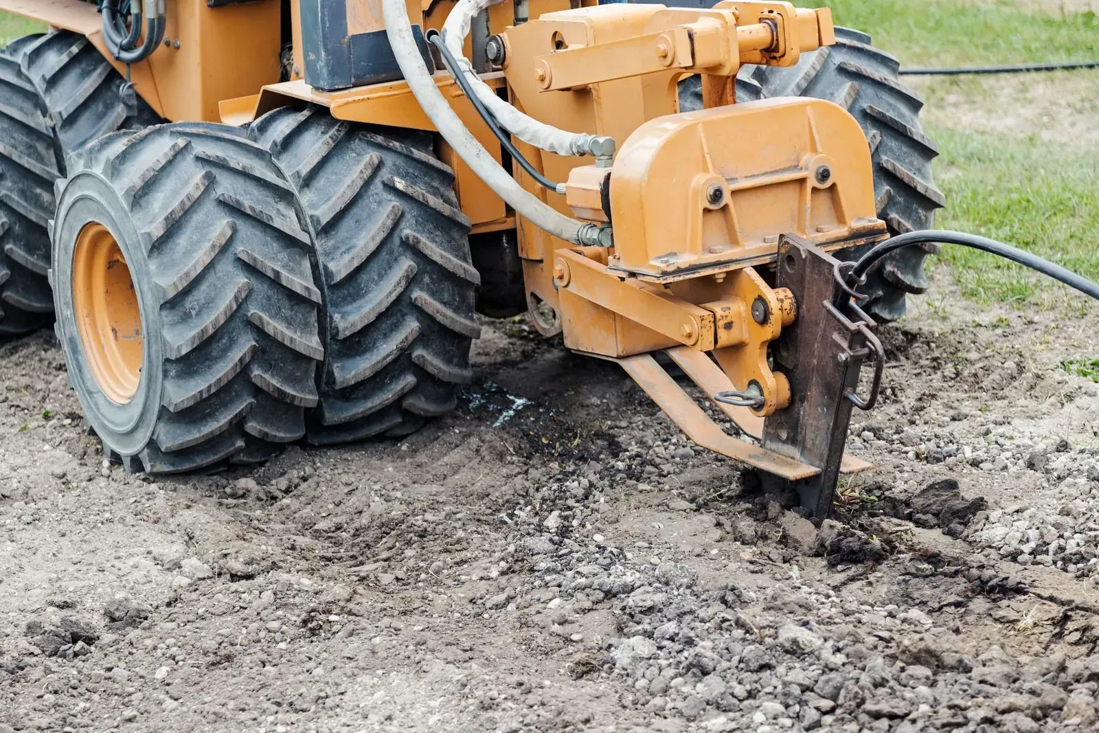 Yellow Caterpillar D6T bulldozer on muddy ground next to a gravel road under a cloudy sky.