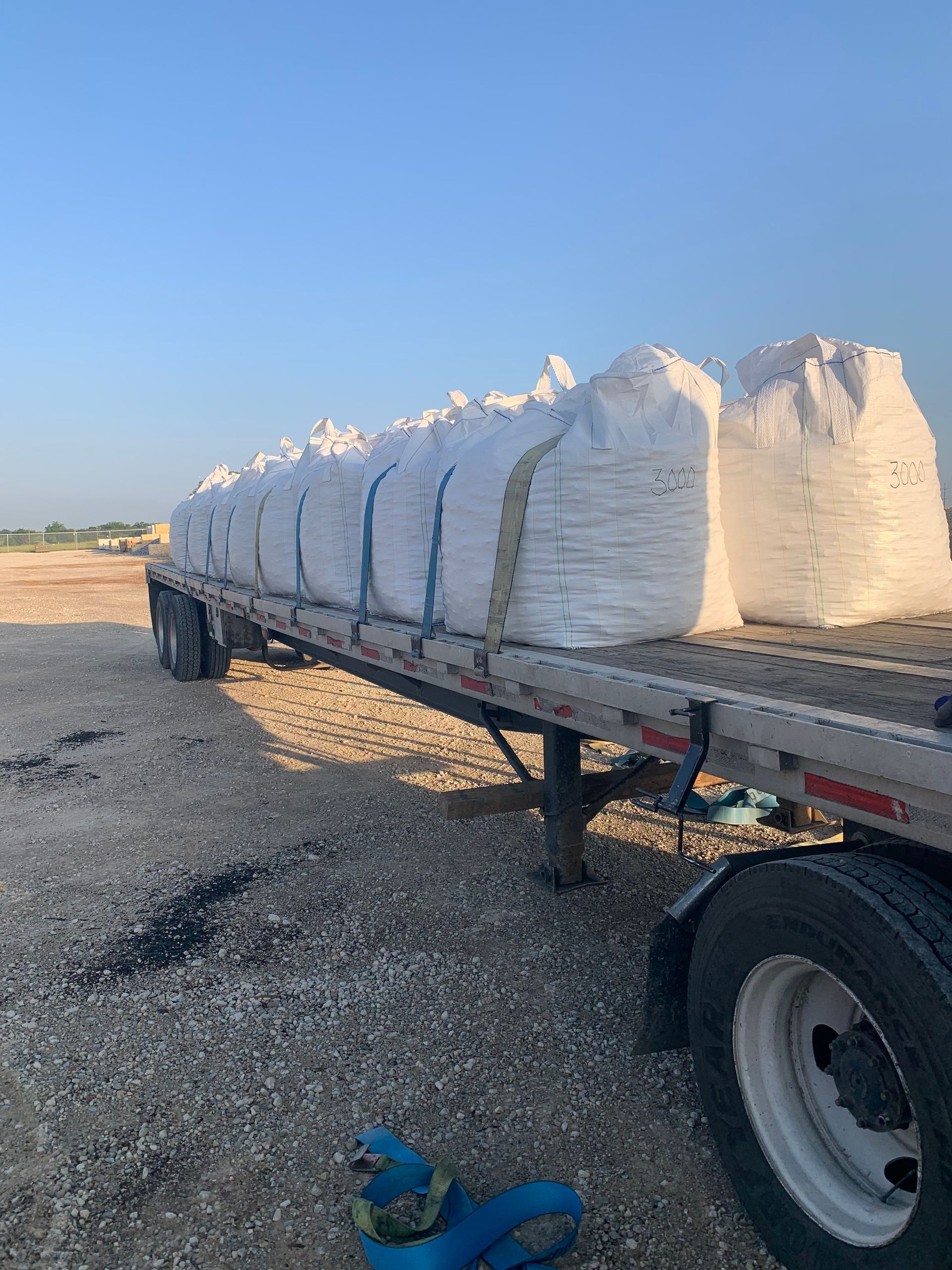 A row of white bags sitting on top of a dirt field.