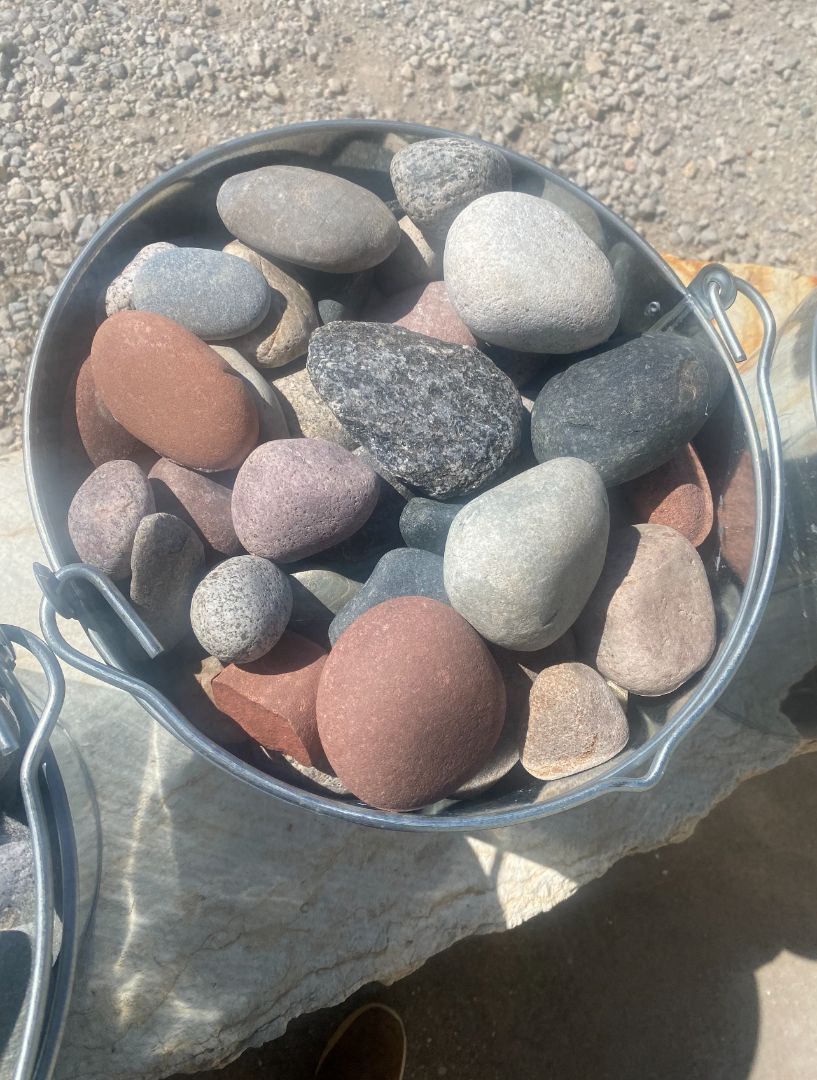 A metal bucket filled with rocks is sitting on a table.