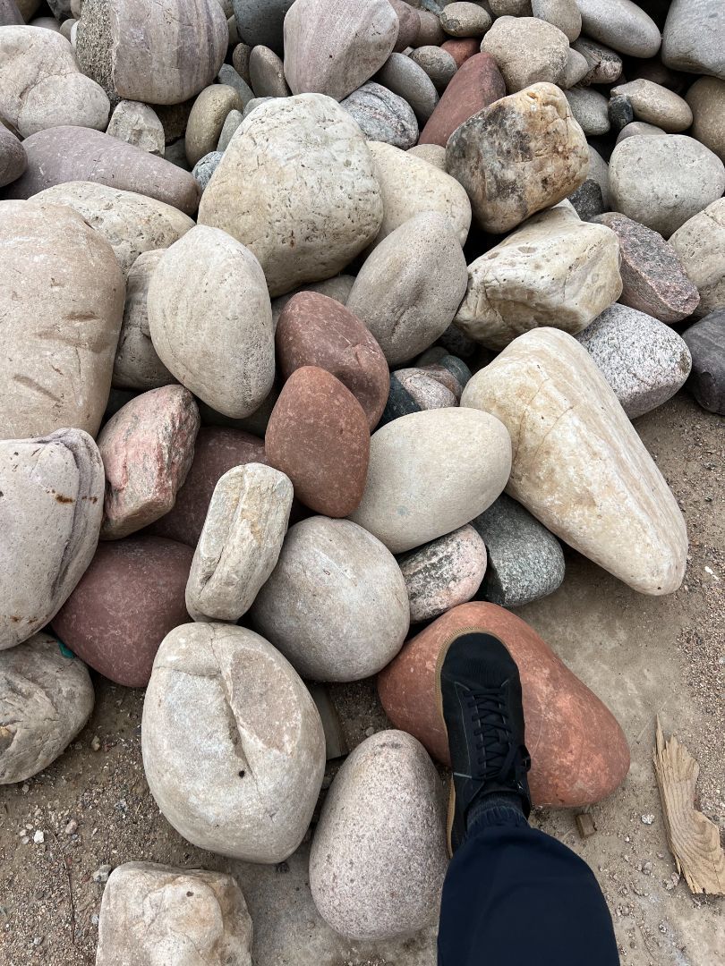 A person is standing in front of a pile of rocks.