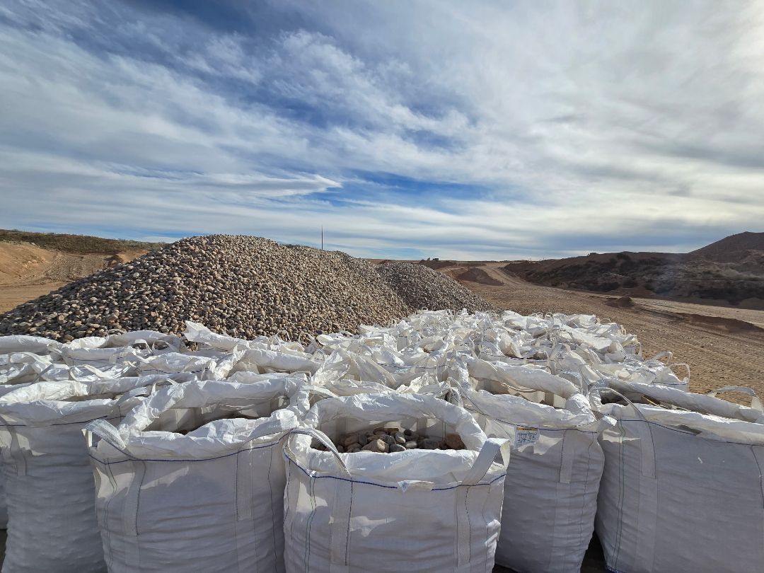 A row of white bags sitting on top of a dirt field.