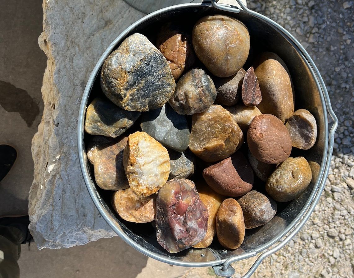 A metal bucket filled with rocks is sitting on a table.