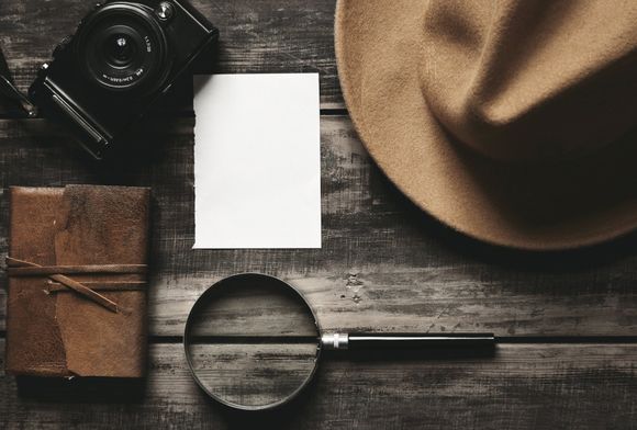 Photo camera, notebook, hat, magnifier, paper on black table - Durham, NC - Arrington Detective Security