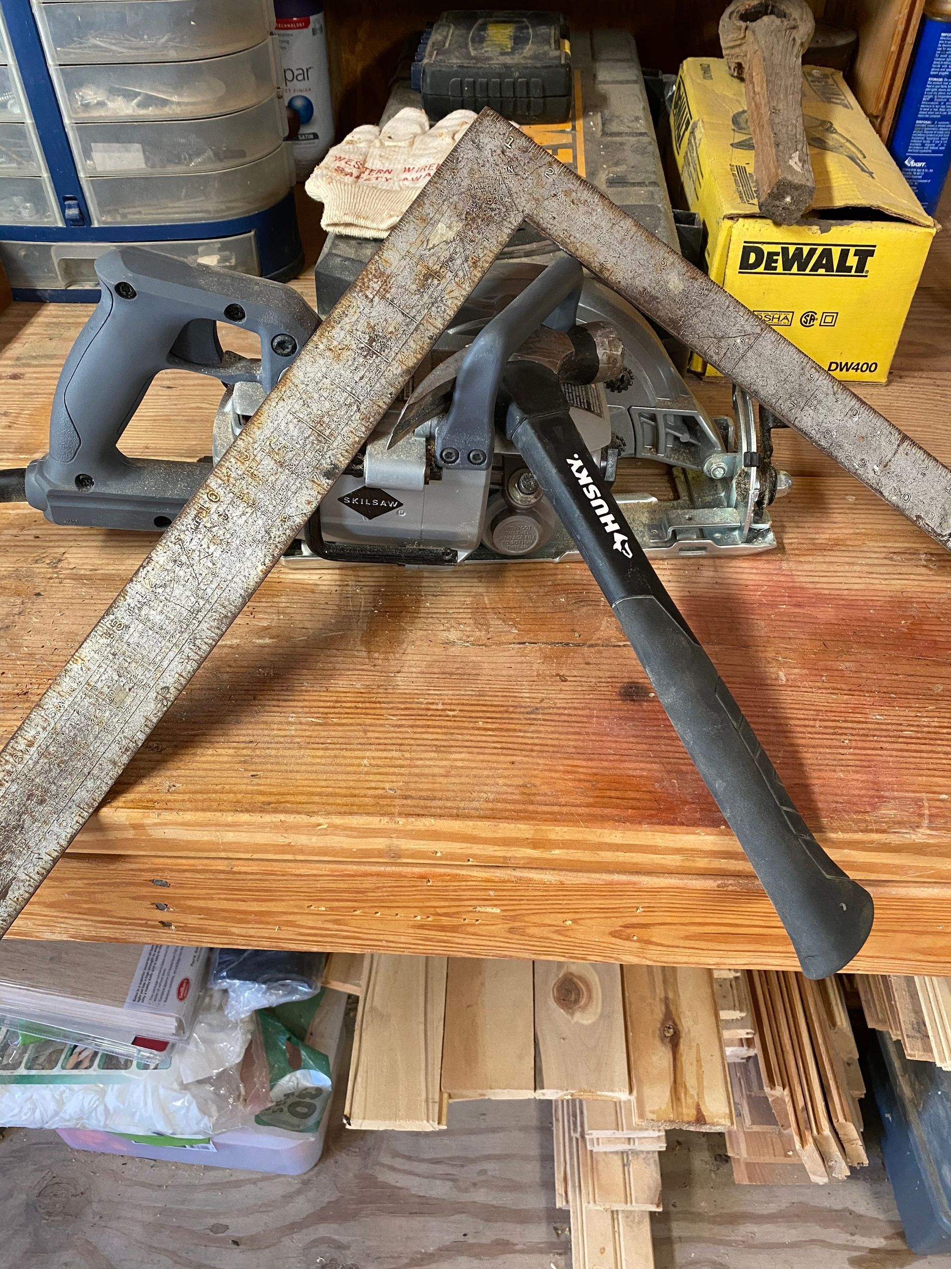 A hammer is sitting on top of a wooden table next to a saw.