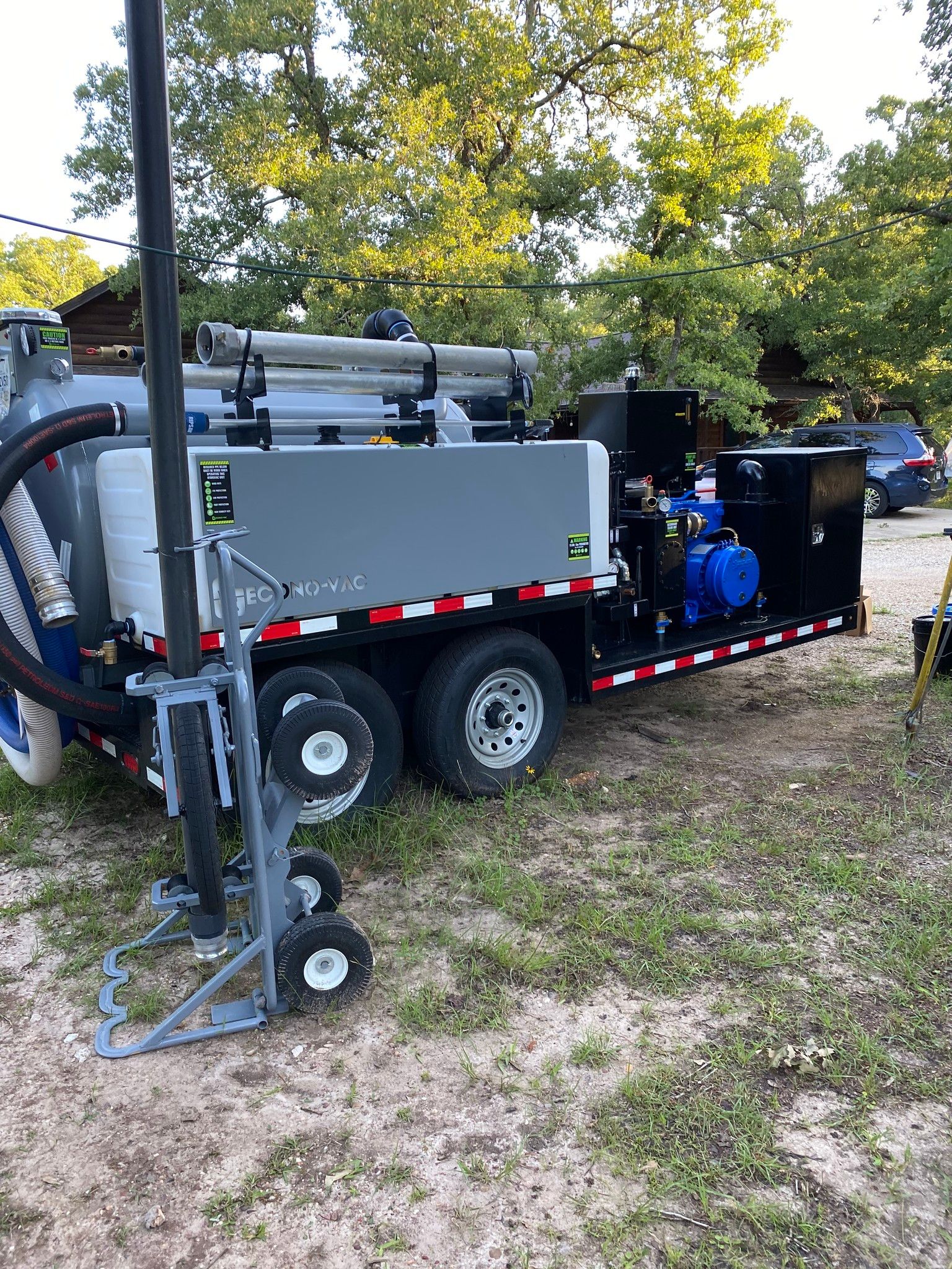 A vacuum truck is parked in a grassy field.