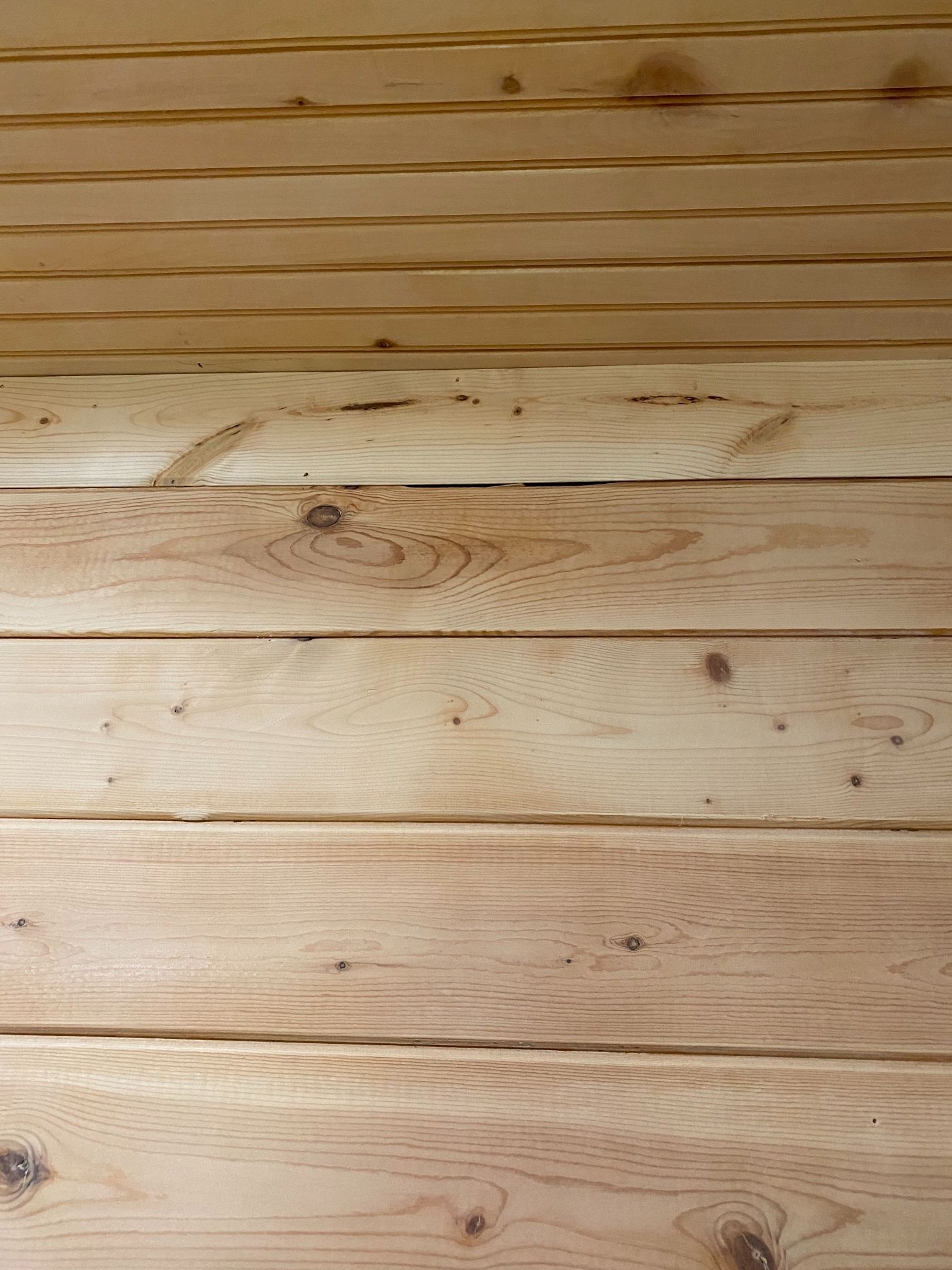 A close up of a wooden floor with a wooden wall in the background.
