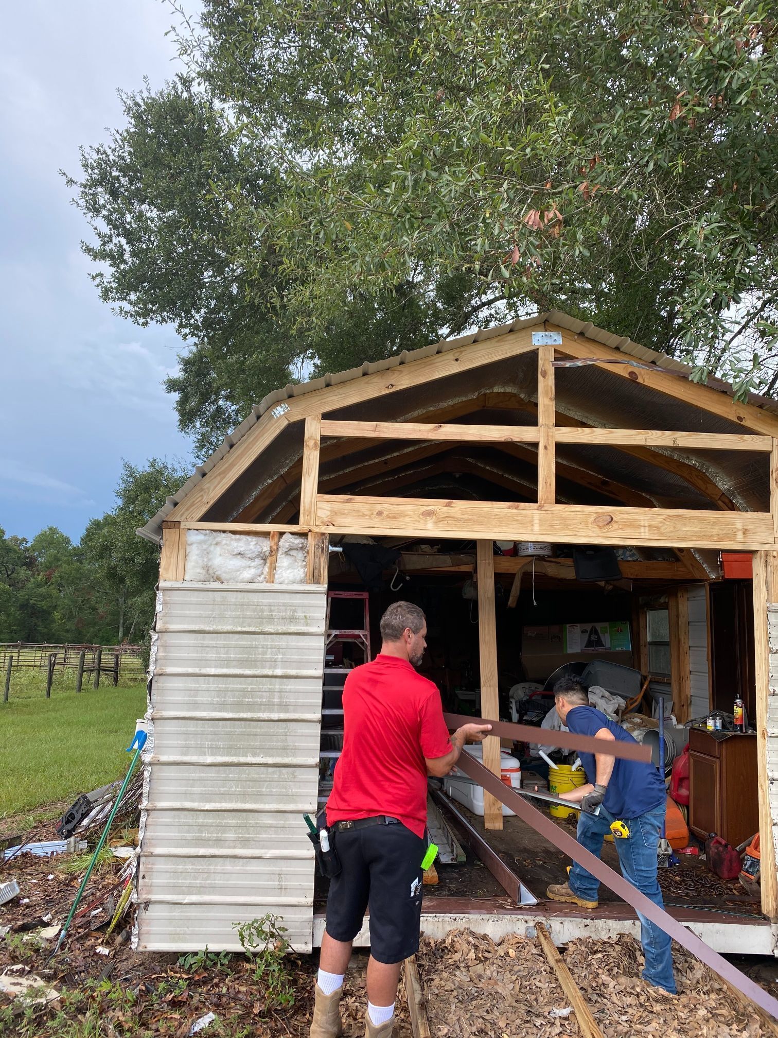 A group of people are working on a shed in a field.
