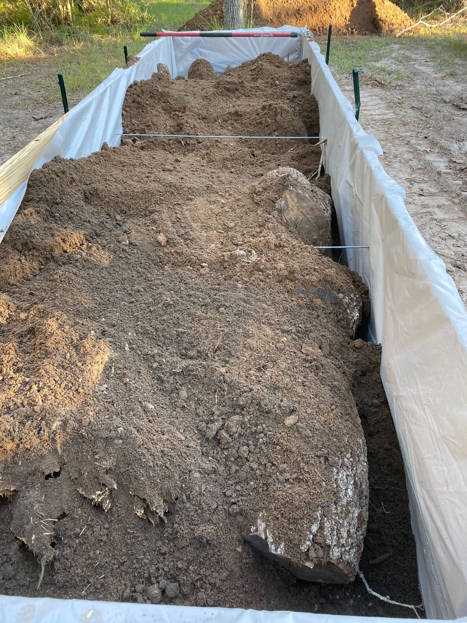 A large pile of dirt is sitting on top of a white tarp.