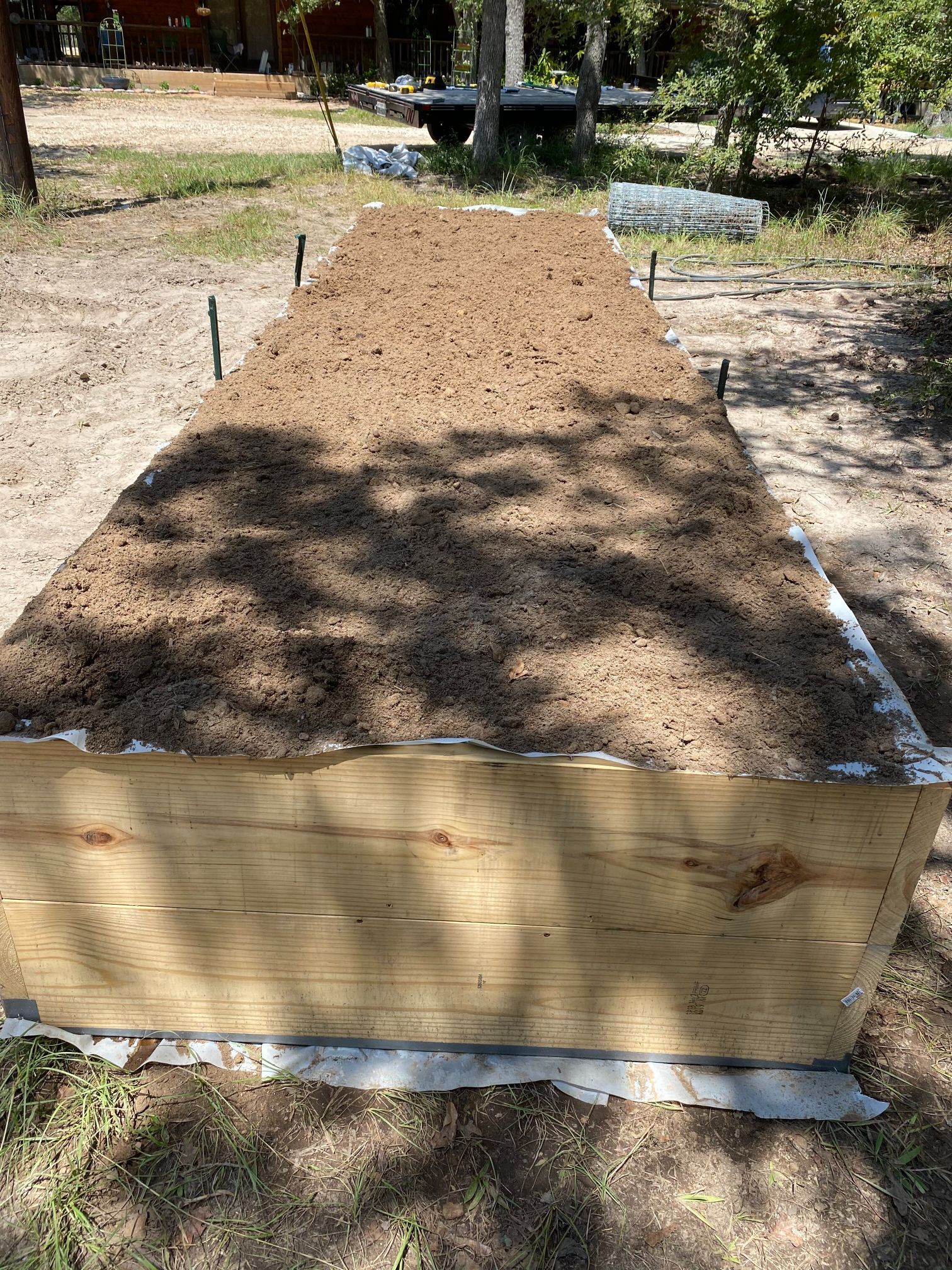 A wooden box filled with dirt is sitting on top of a dirt field.