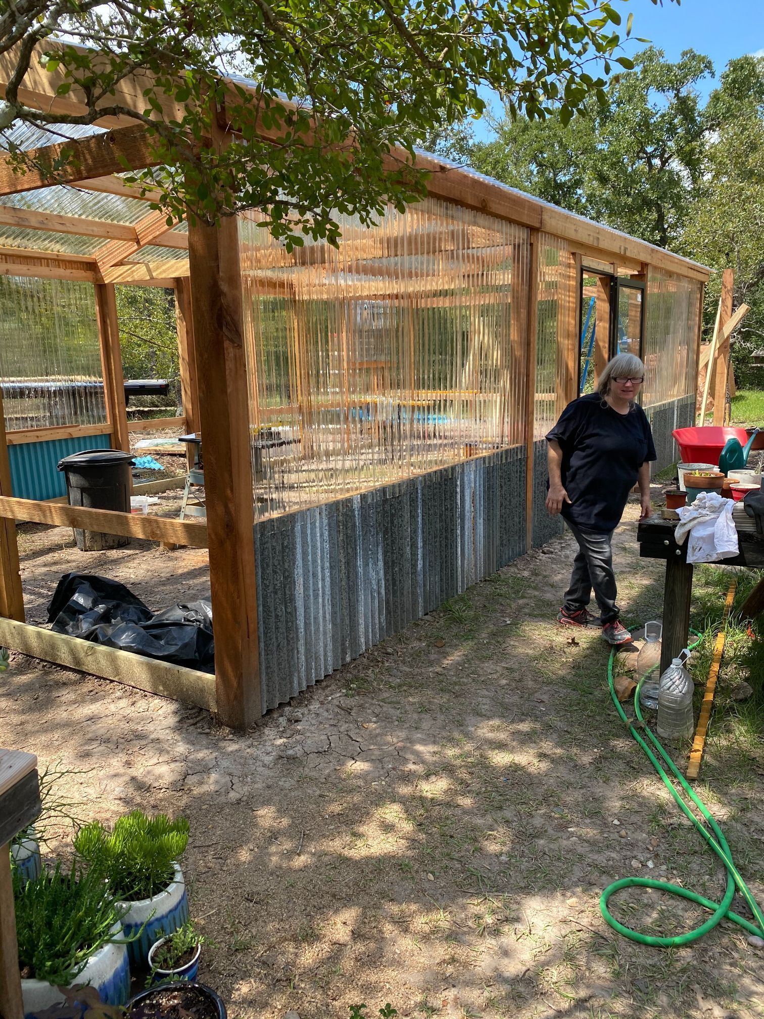 A man is standing in front of a greenhouse.