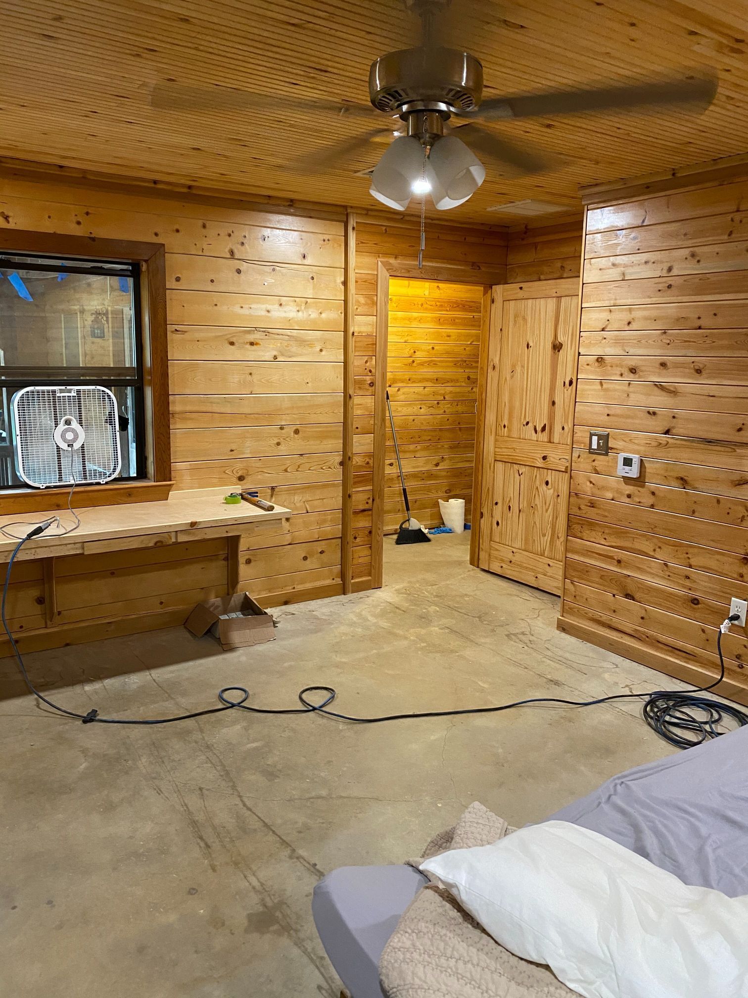 A bedroom in a log cabin with a ceiling fan and a bed.