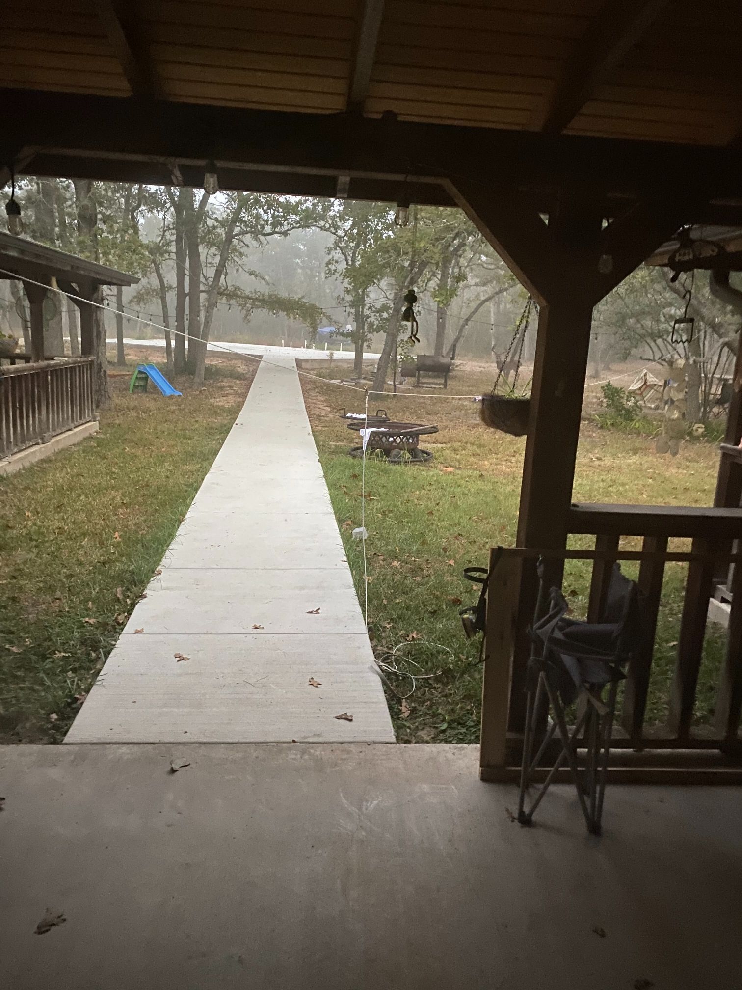 A view of a walkway from a porch with a wheelchair in the foreground.