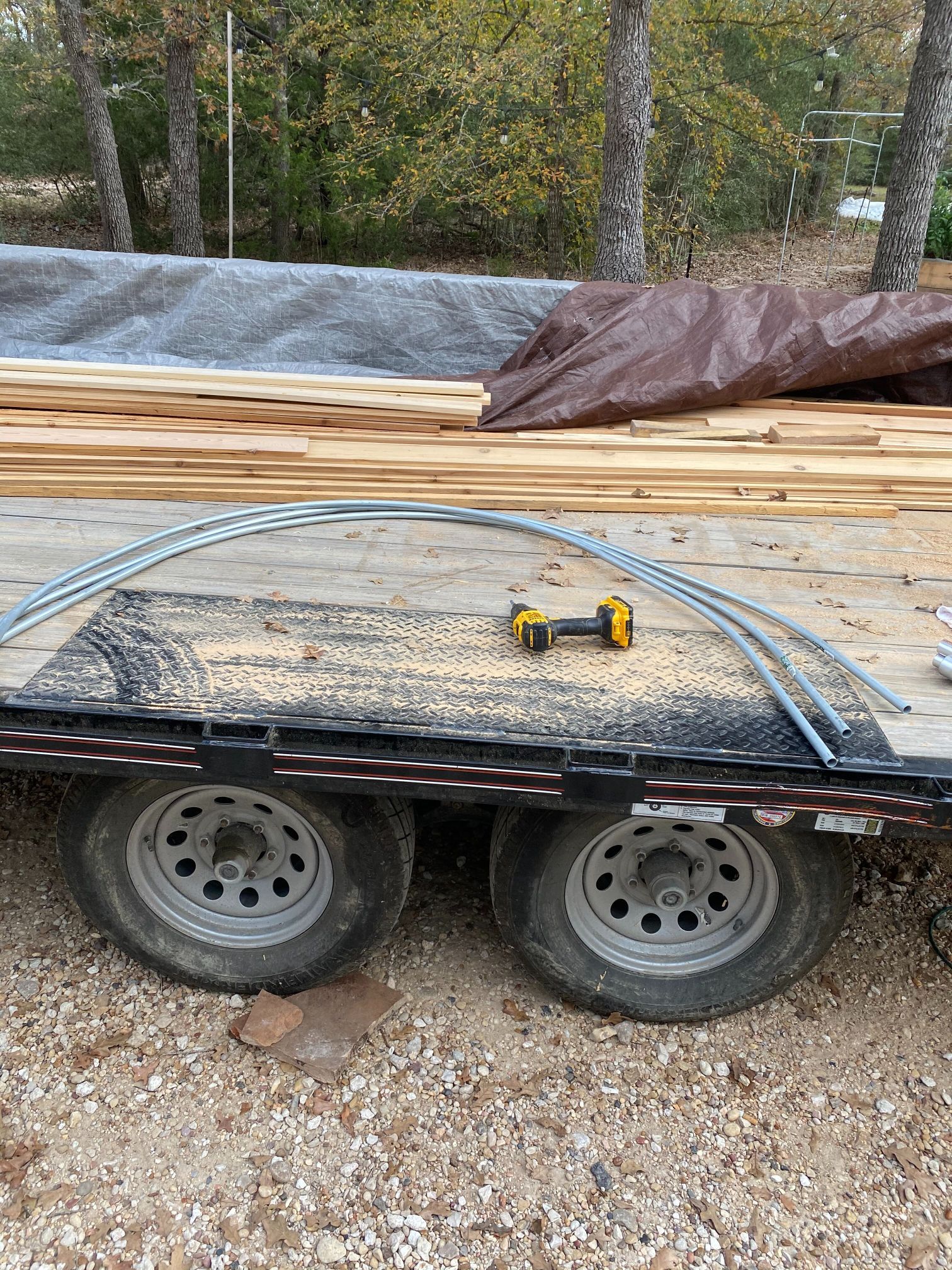 A trailer filled with wood and a drill on top of it.