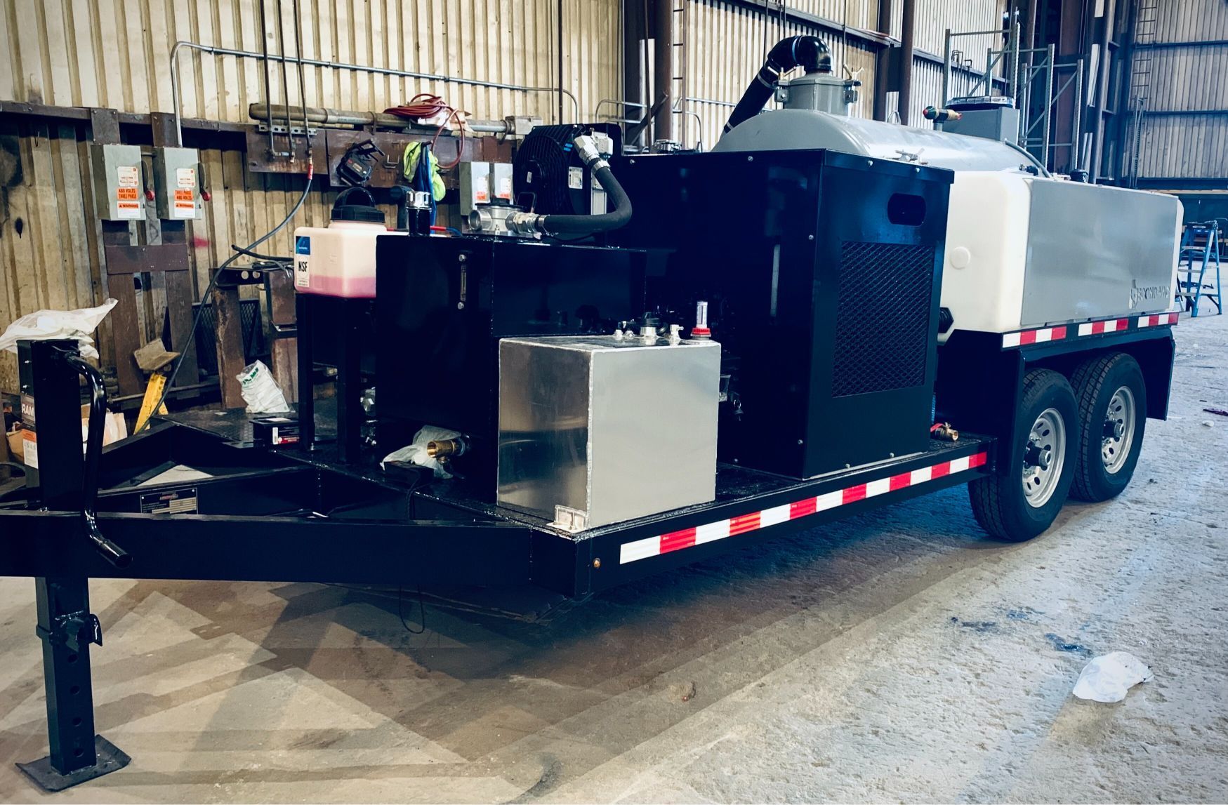 A trailer with a machine on it is parked in a garage.