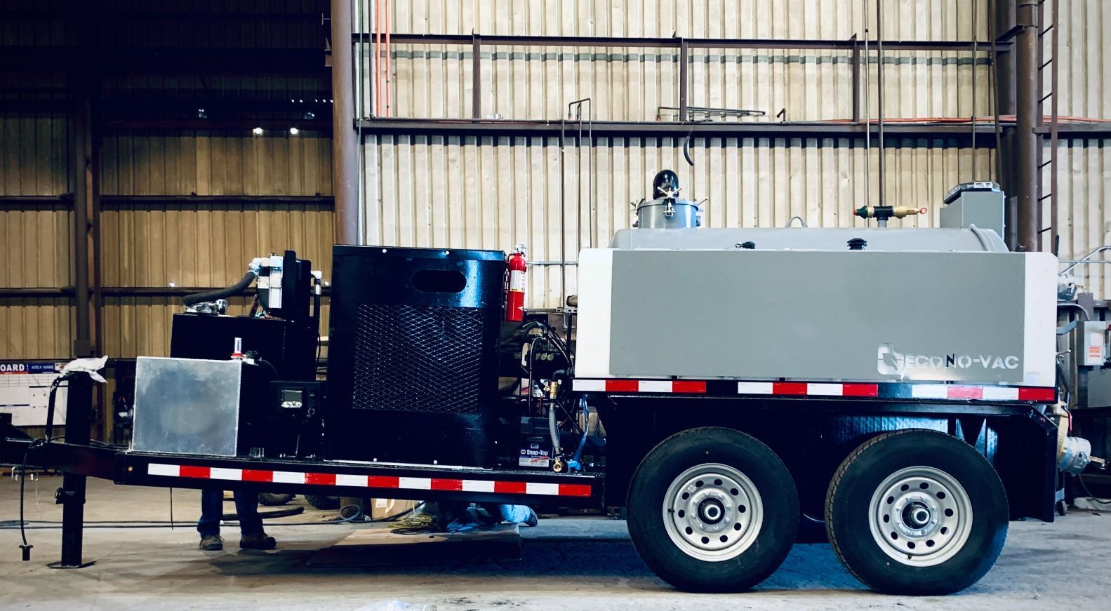 A trailer with a machine on it is parked in a warehouse.