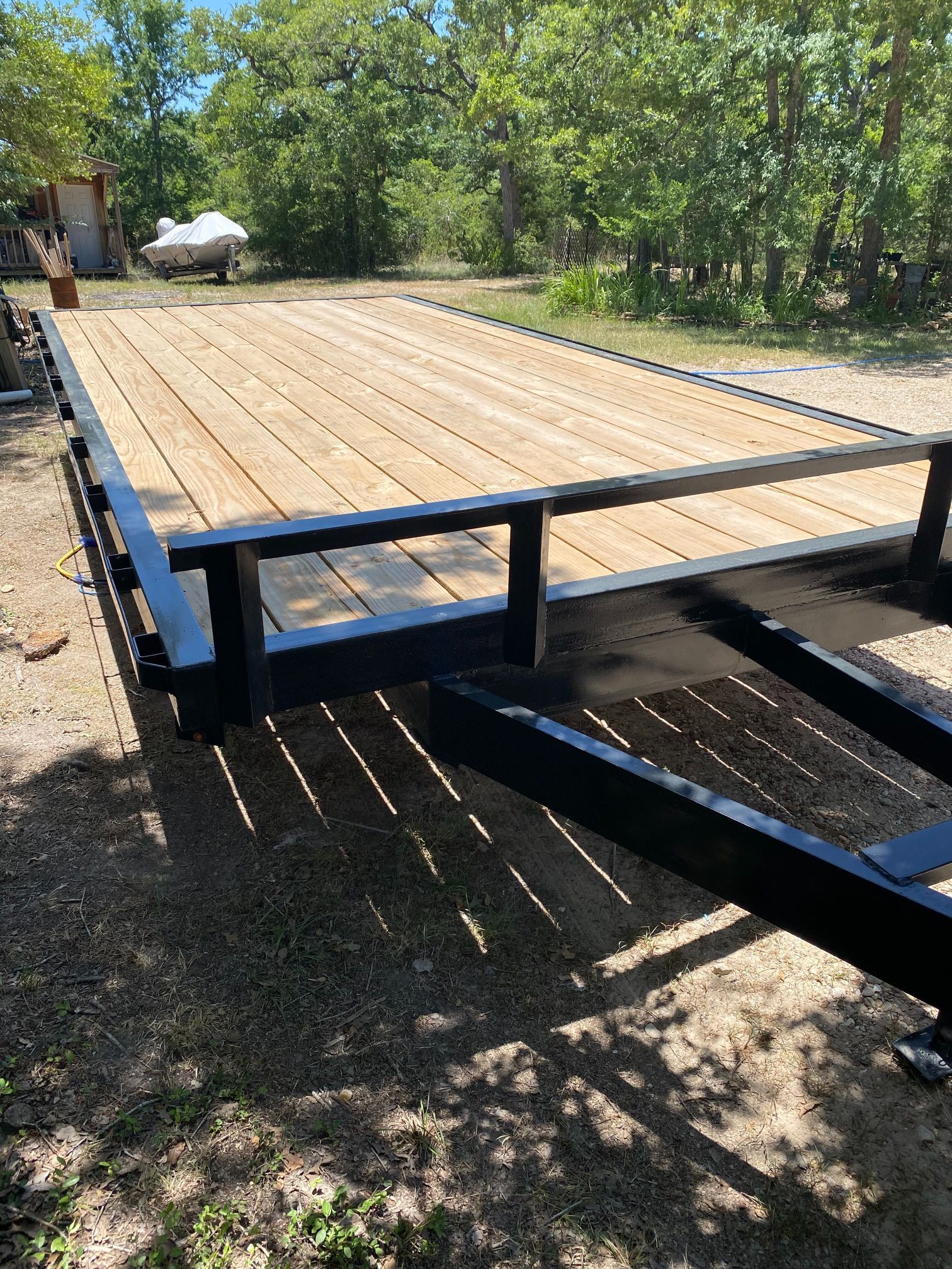 A wooden trailer is sitting on top of a dirt field.