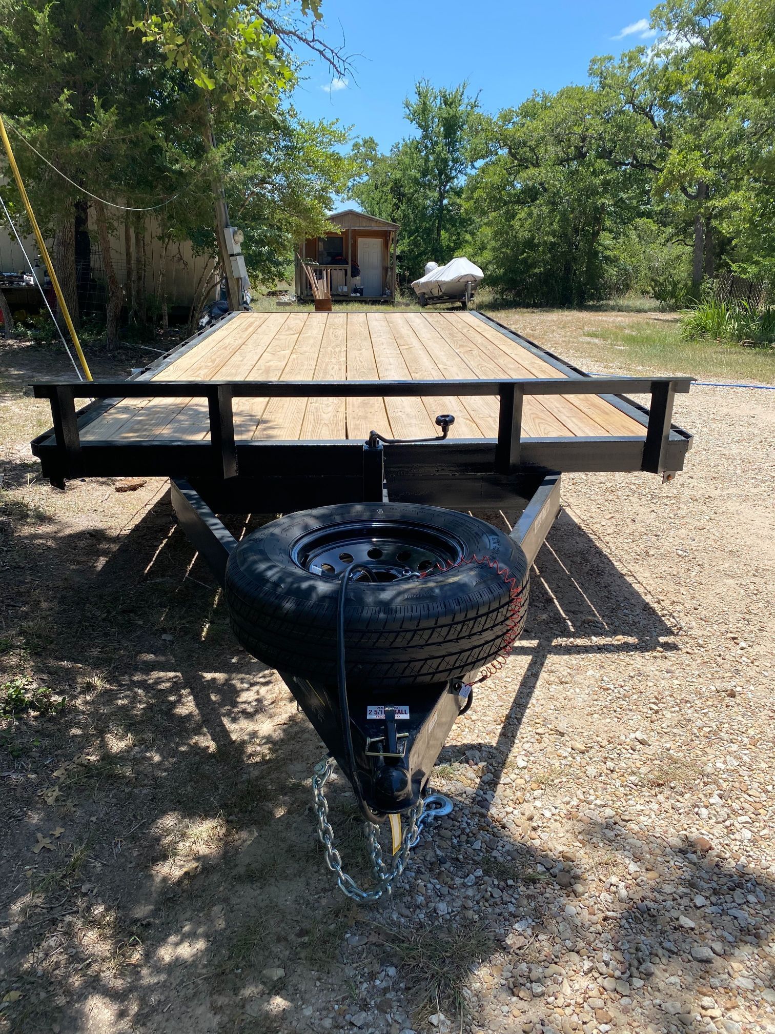 A trailer with a tire attached to it is parked in a dirt field.