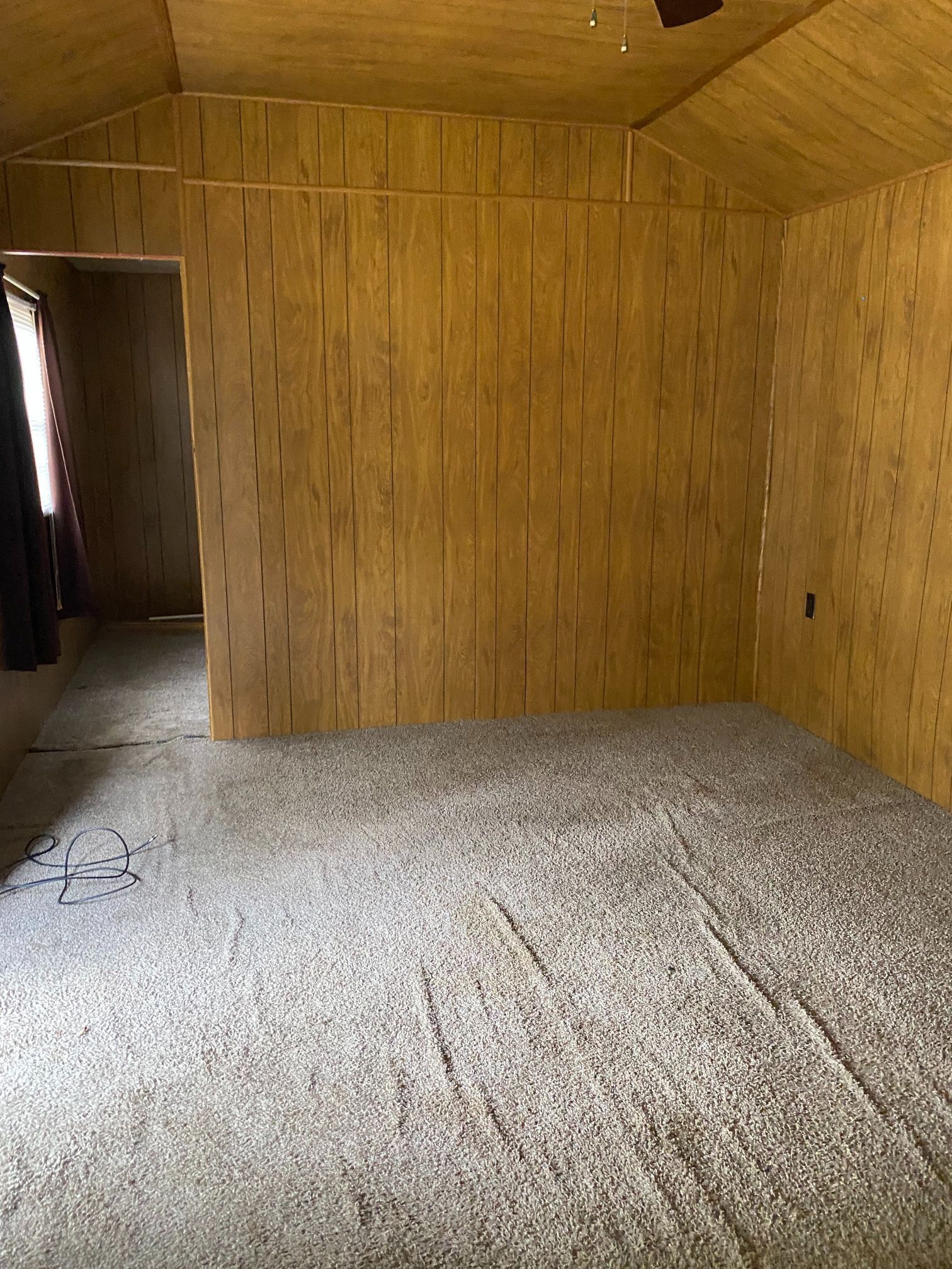 An empty room with wooden walls and a carpeted floor.