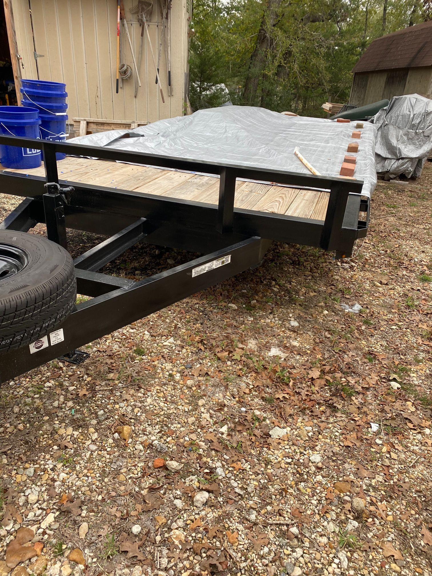 A trailer is parked in a gravel lot in front of a building.