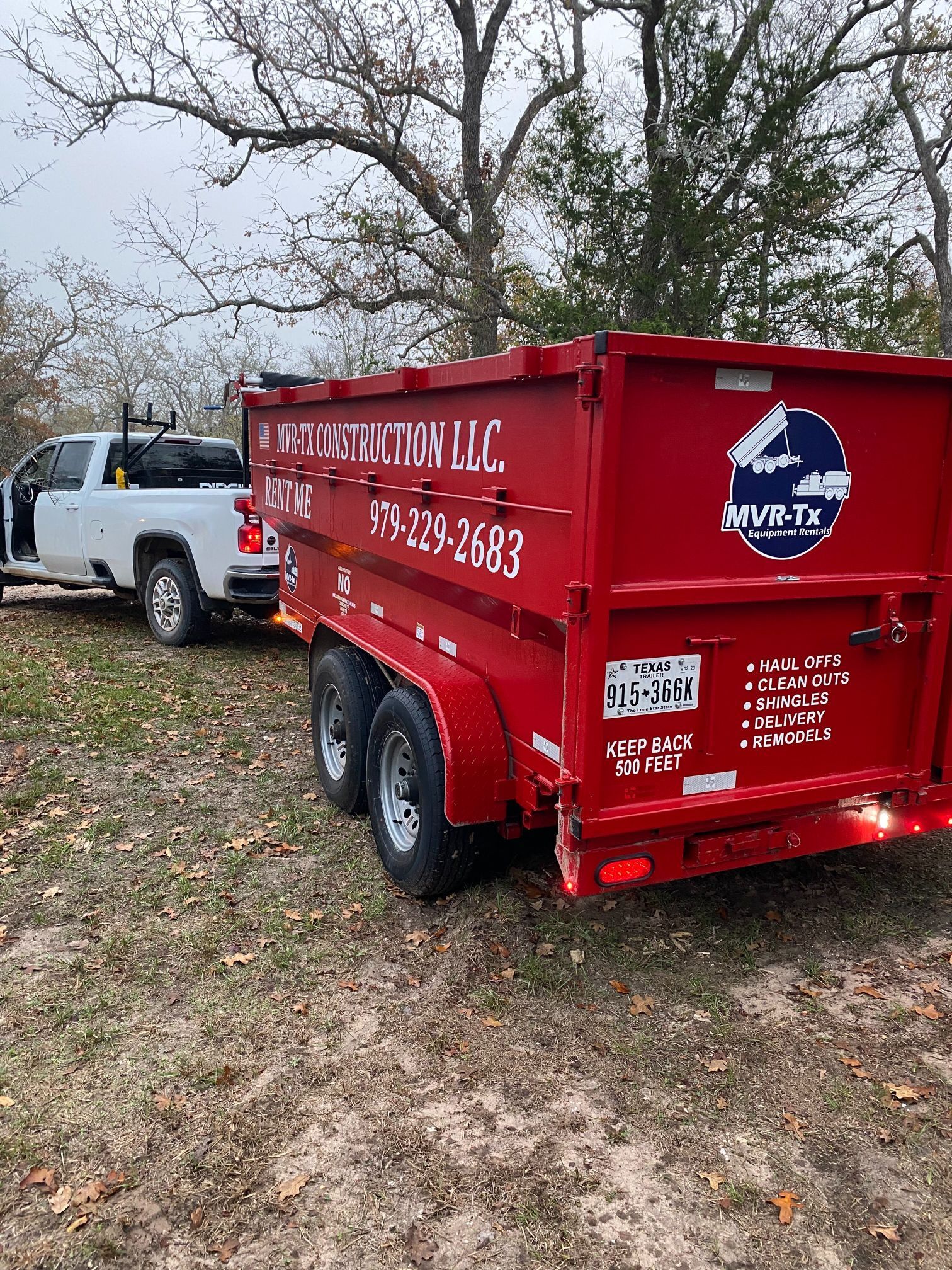 A red dumpster is being towed by a white truck.
