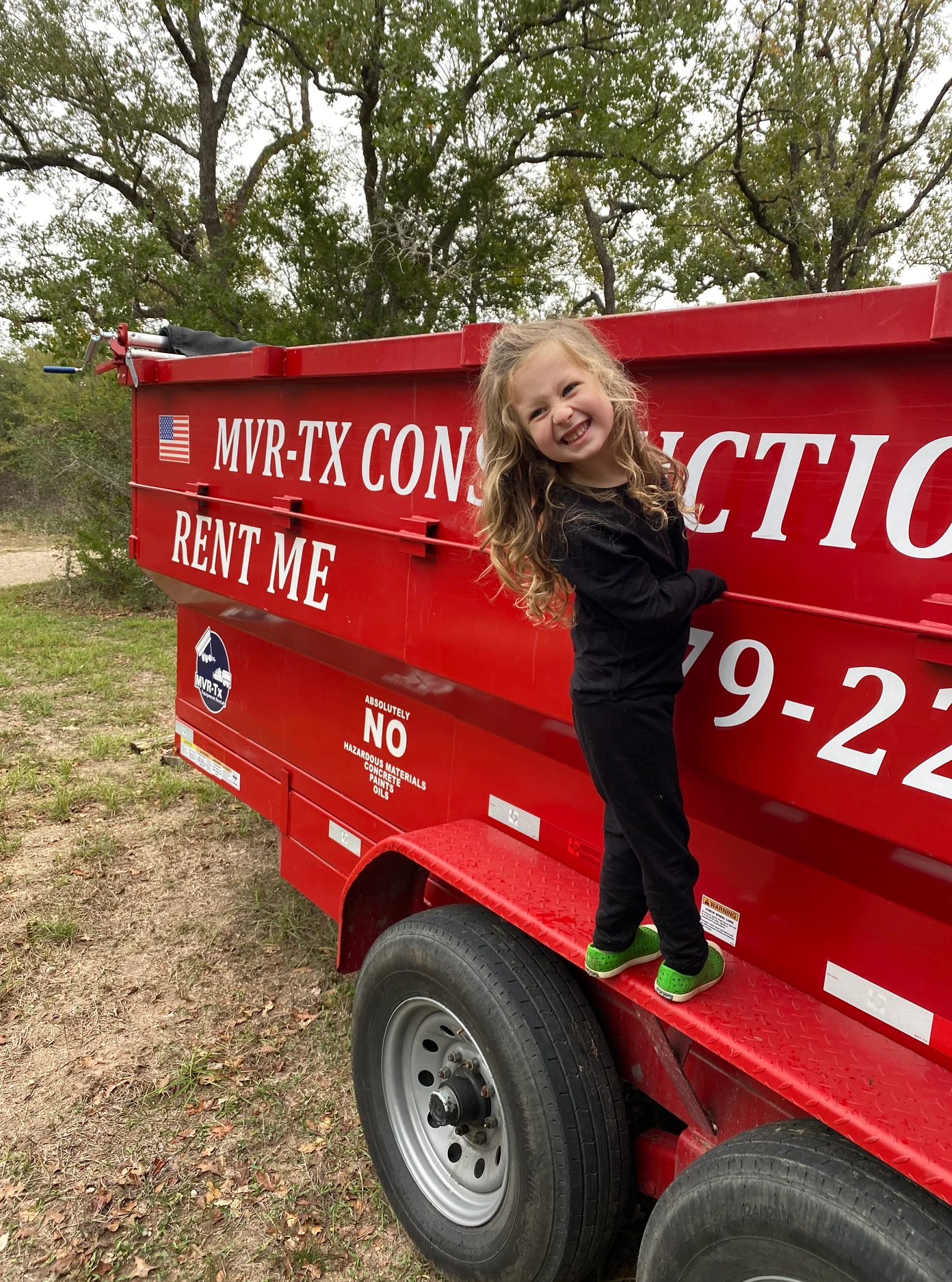 A red dumpster is being towed by a white truck.