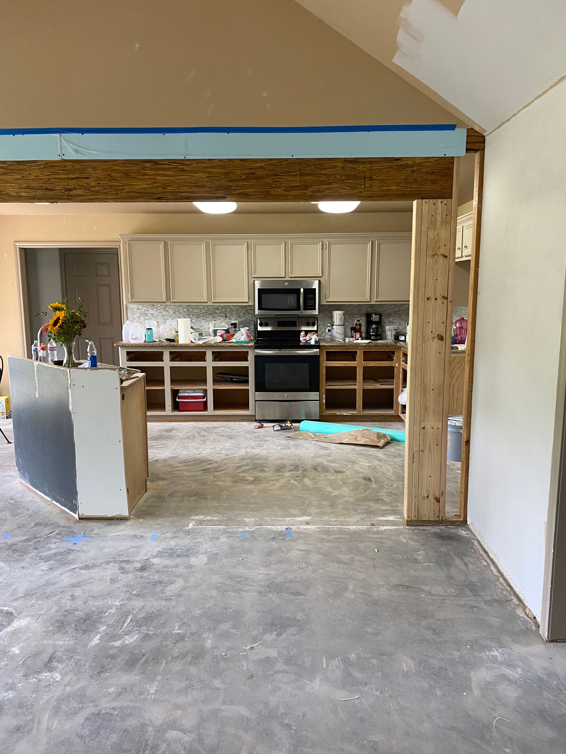 A kitchen under construction with stainless steel appliances and white cabinets.