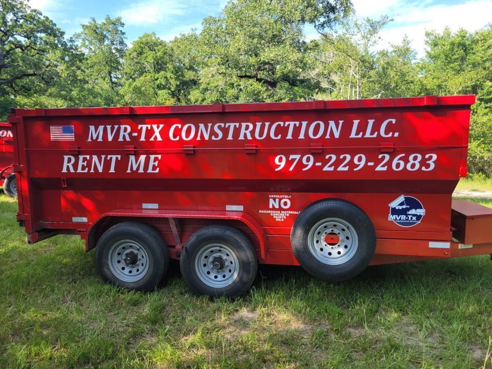 A red dumpster from mvr-tx construction llc is parked in the grass