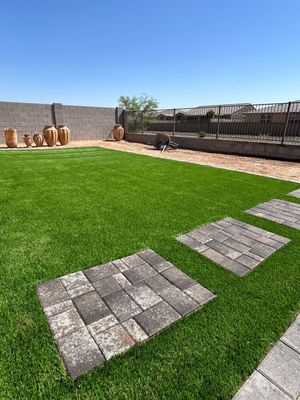 A backyard with a lush green lawn and brick walkways.