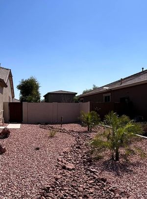 A backyard filled with rocks and palm trees on a sunny day