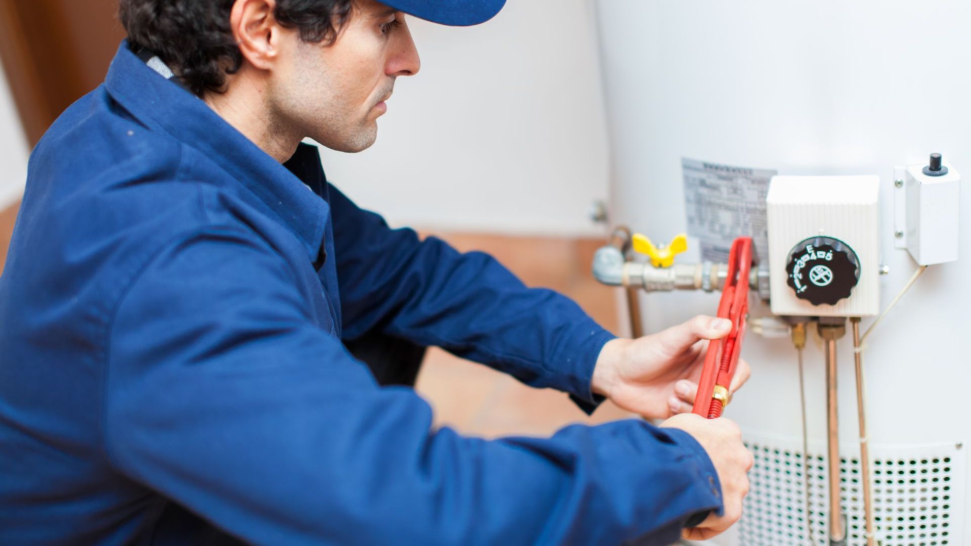 A man is fixing a water heater with a wrench.