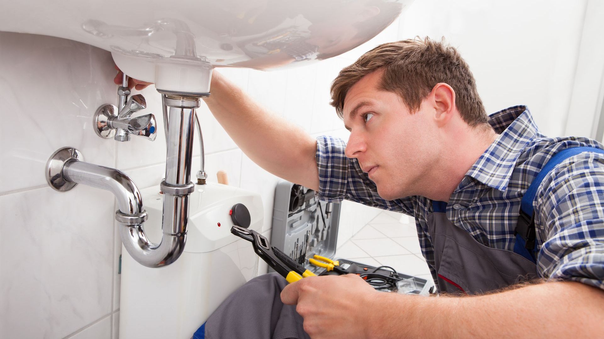 A plumber is fixing a sink in a bathroom.