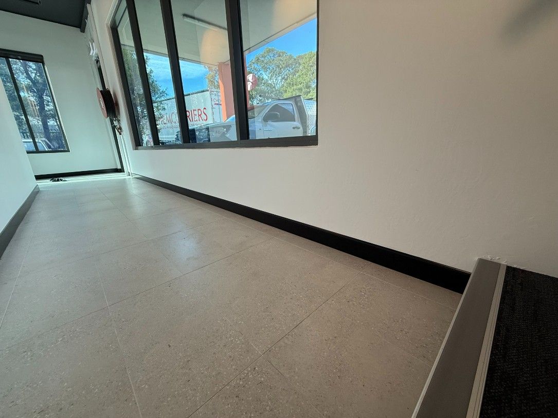 A Hallway With a White Floor and Black Trim and a Window — JOA - Construction & Maintenance in Appin, NSW