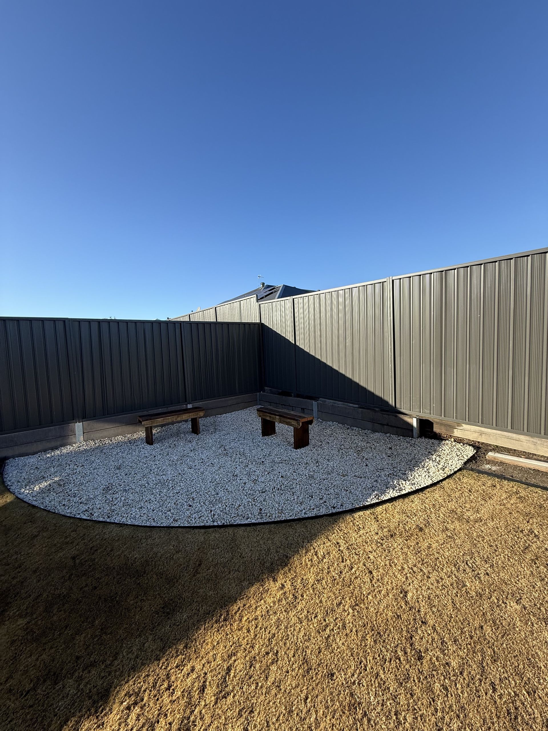 There is a fence in the background and a circle of gravel in the middle of the yard. — JOA - Construction & Maintenance in Campbelltown, NSW