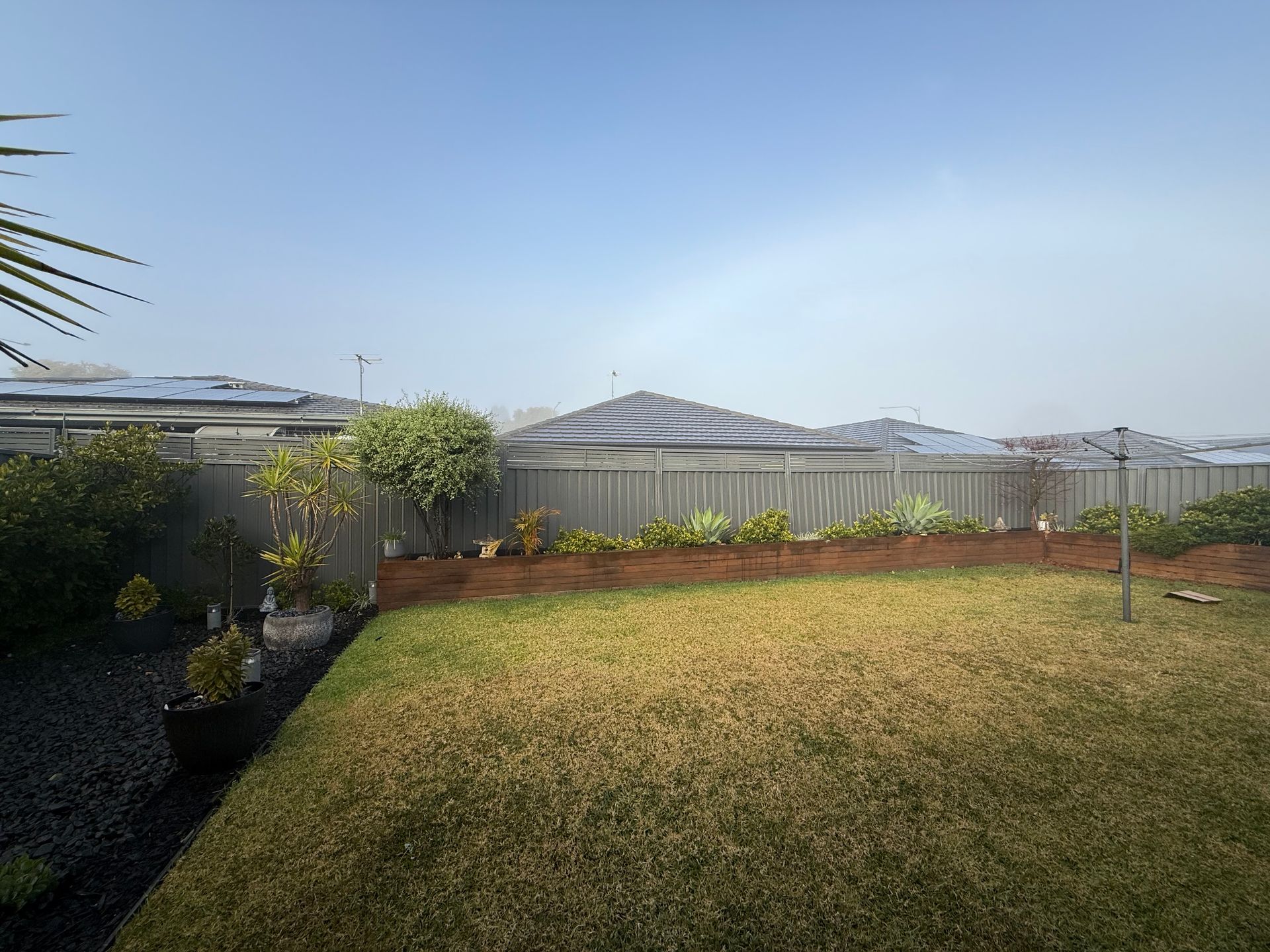 A backyard with a fence and a lot of grass — JOA - Construction & Maintenance in Campbelltown, NSW