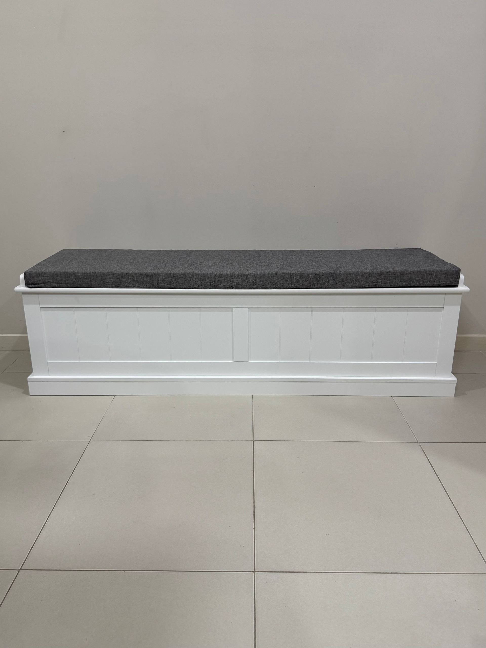 A white bench with a grey cushion is sitting on a tiled floor. — JOA - Construction & Maintenance in Campbelltown, NSW