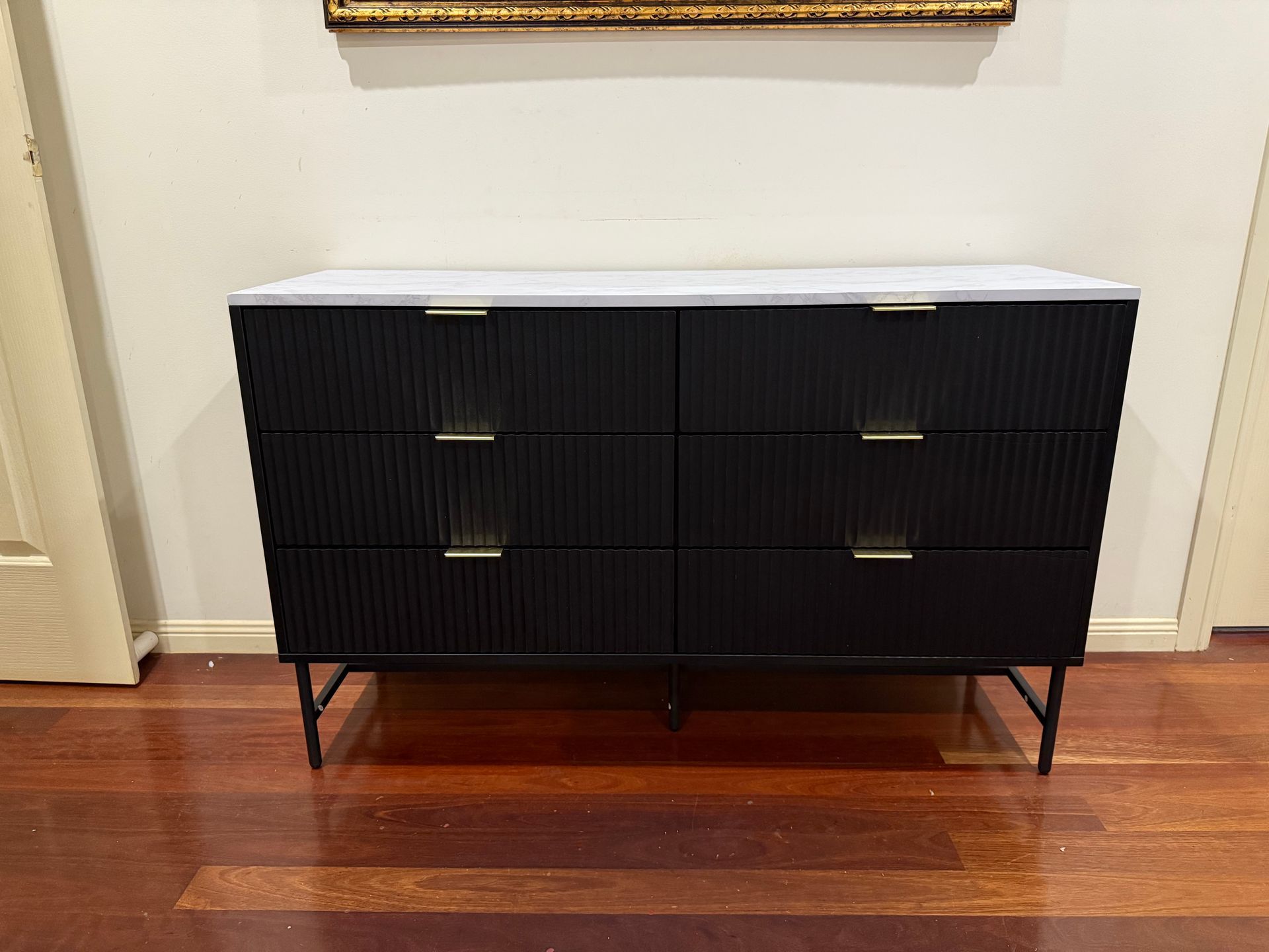 A black dresser with a white top is sitting on a wooden floor. — JOA - Construction & Maintenance in Appin, NSW