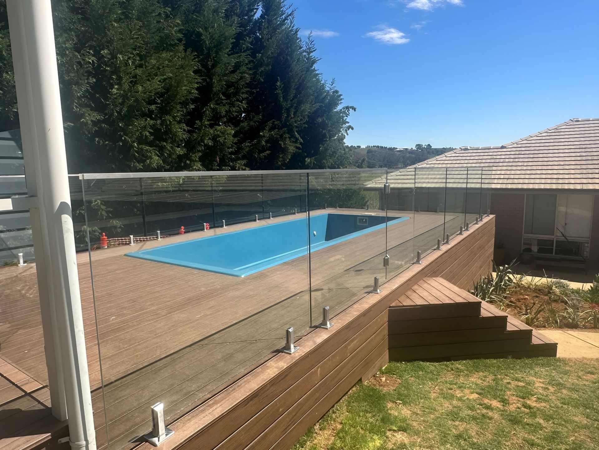 Large pool with glass railing and a View of a bricked house — Canobolas Glass Service In Orange, NSW