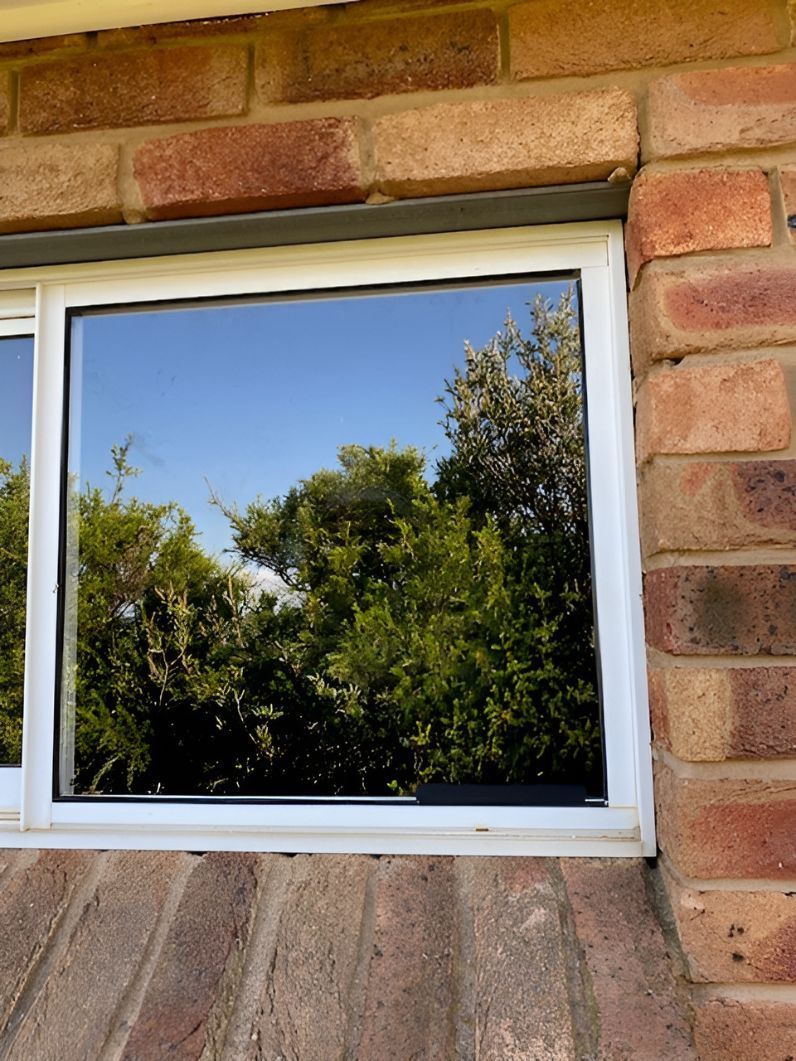 A Window on a Brick Wall With Trees Reflected in the Window — Canobolas Glass Service In Orange, NSW