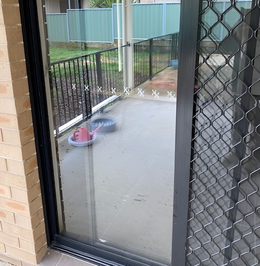 A Sliding Glass Door With a Fence Behind It — Canobolas Glass Service In Orange, NSW