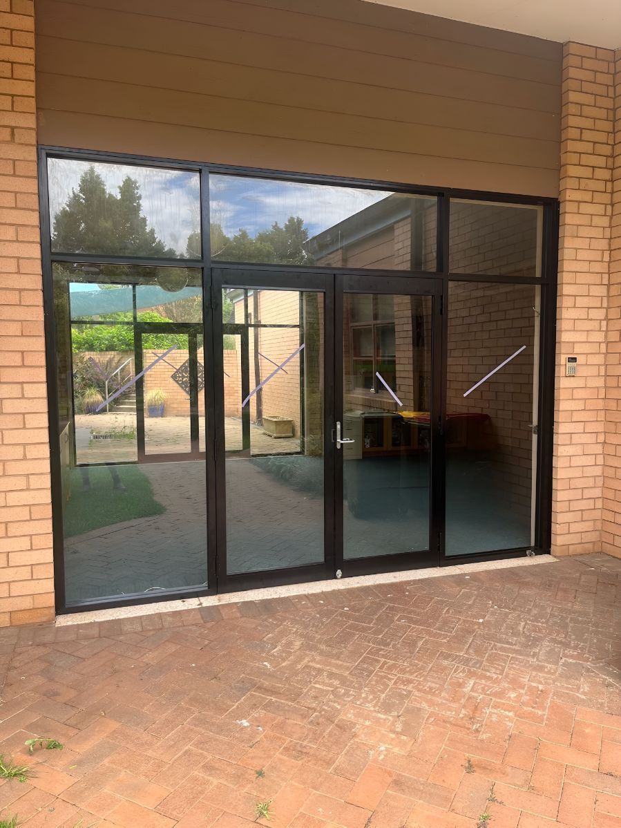 A Brick Building With a Lot of Windows and Sliding Glass Doors — Canobolas Glass Service In Orange, NSW