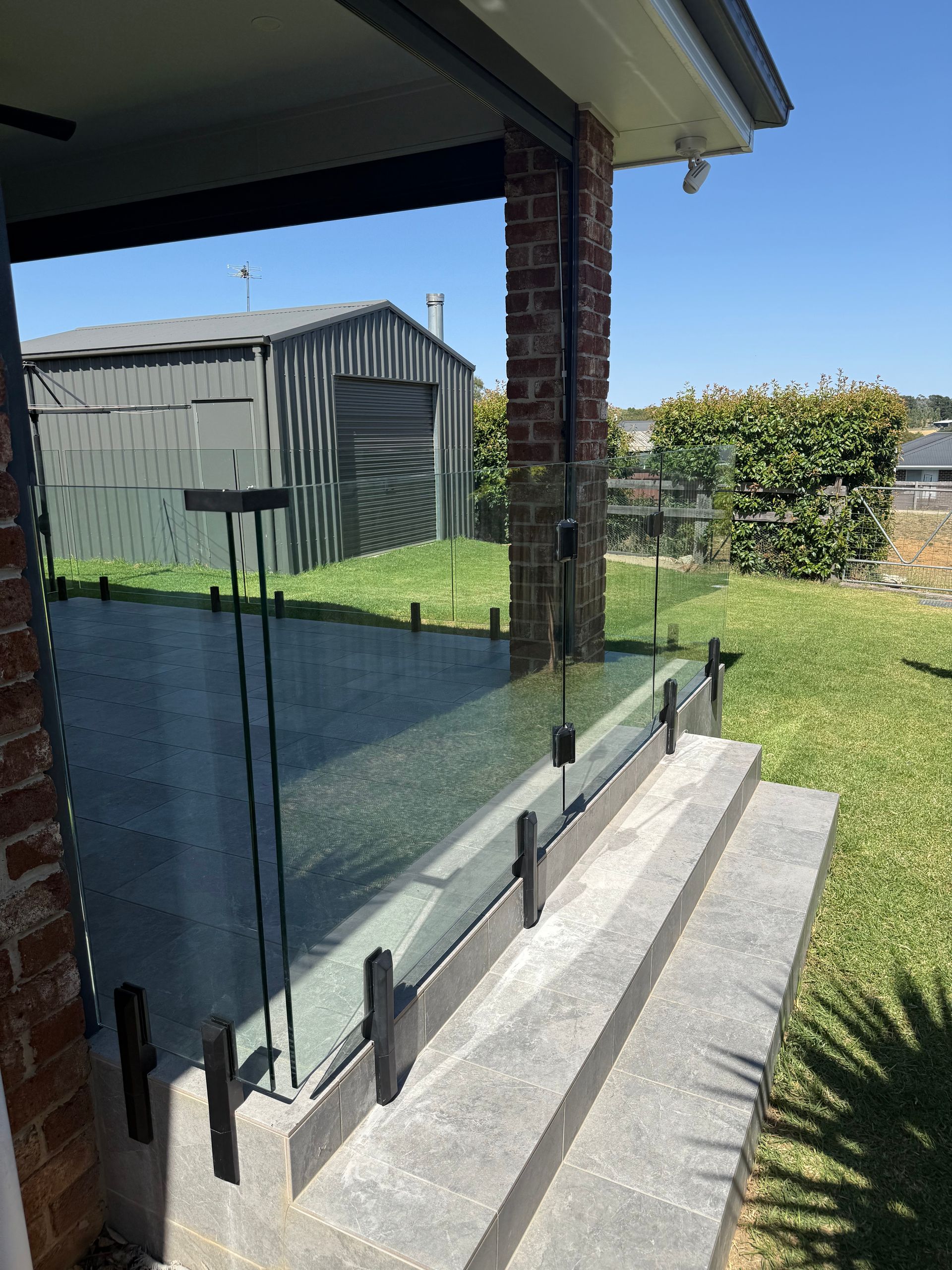 A Patio With a Glass Railing and a shed in the Background — Canobolas Glass Service In Orange, NSW