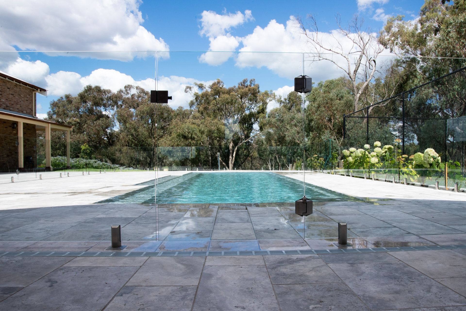 A Large Swimming Pool is Surrounded by a Glass Fence — Canobolas Glass Service In Orange, NSW