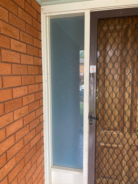 Brick wall next to a frosted window and a screened door.