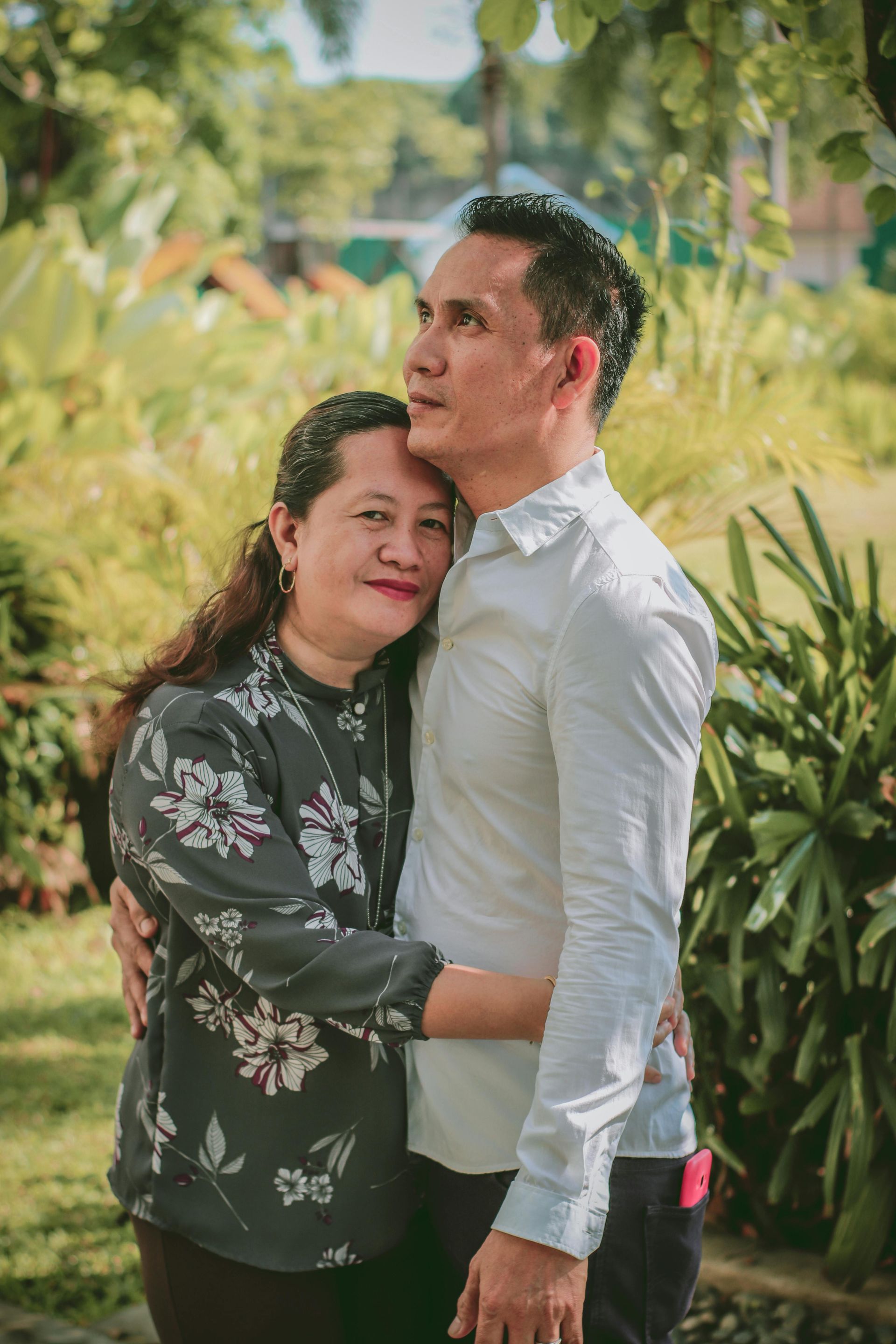 A man and a woman are hugging each other in a park.