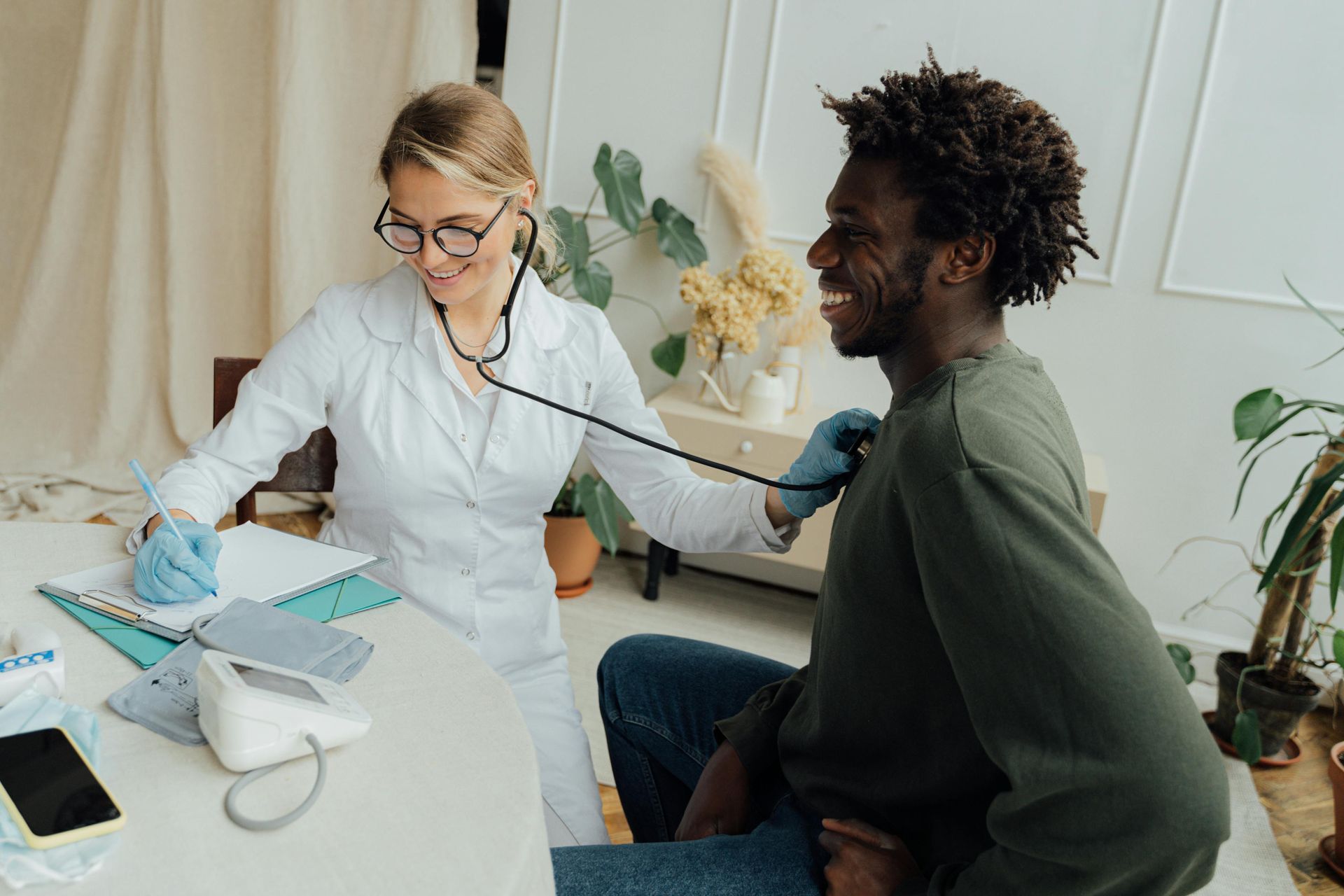 A doctor is listening to a man 's heartbeat with a stethoscope.