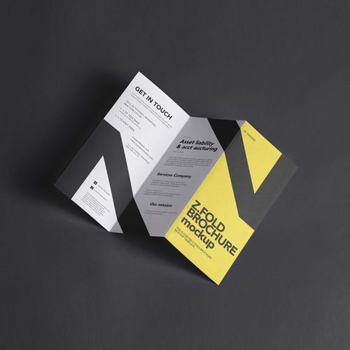 A folded brochure mockup is sitting on a black surface.