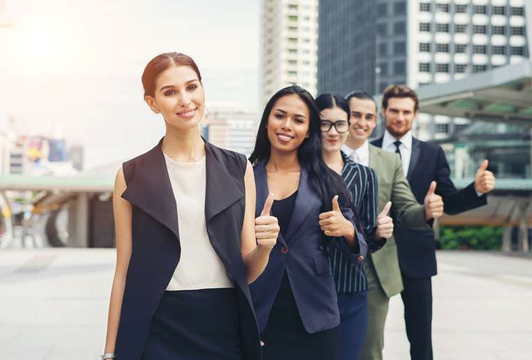 A group of business people are standing next to each other and giving a thumbs up.