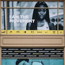 A woman is standing in front of a window with a sign that says `` i am the movement ''.