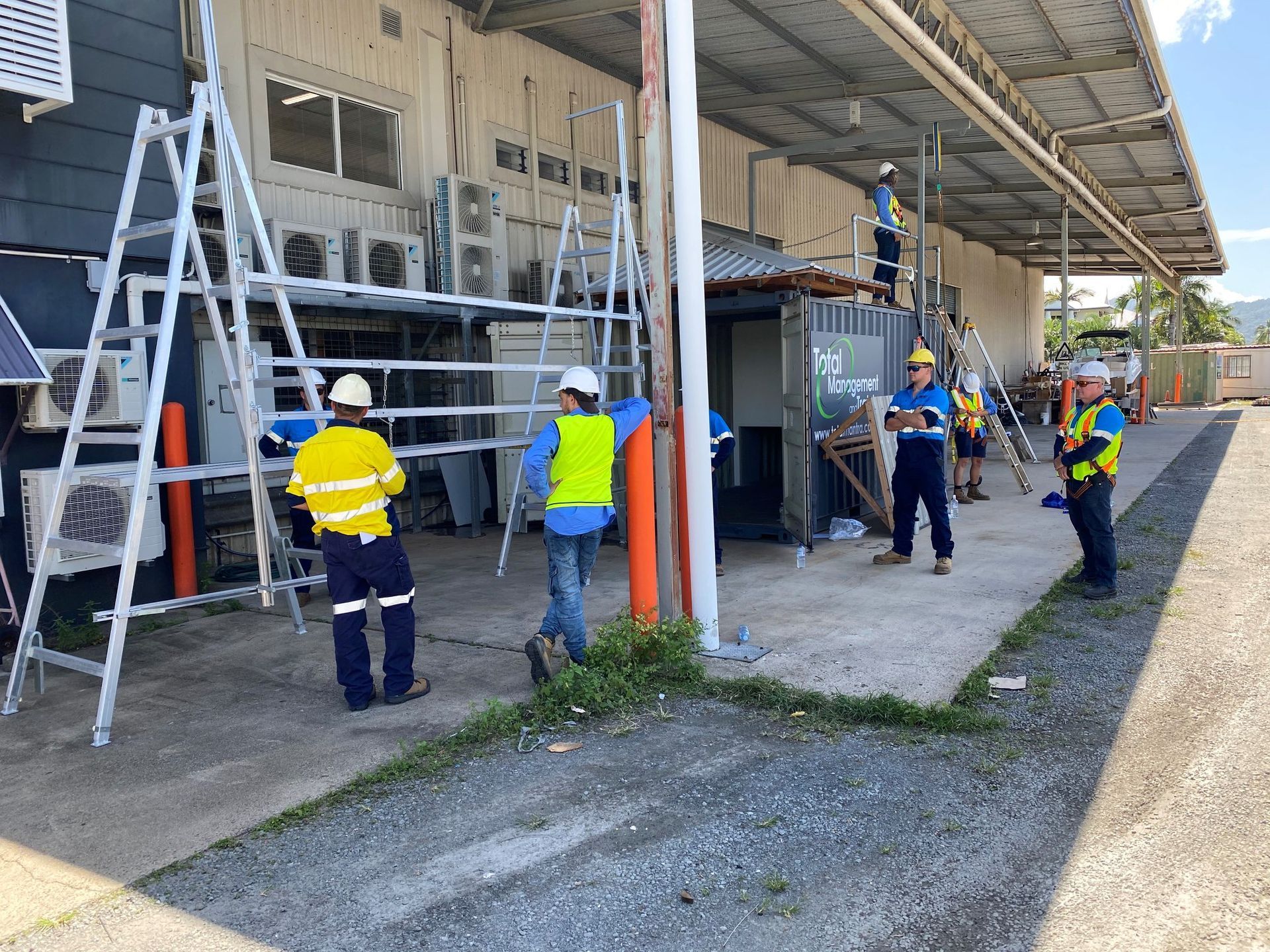 Workers Using a Crane Lift a Large, Boxed Unit onto A Building Roof — MAE Refrigeration In Portsmith, QLD